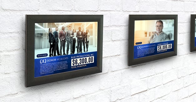 Two donor plaques hanging on a white brick wall.